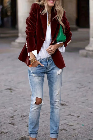Burgundy velvet blazer with sculpted shoulders and button details, styled with jeans.
