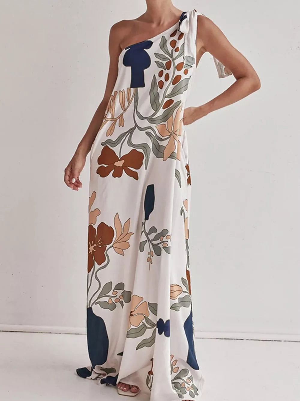Elegant one-shoulder maxi dress with a floral print and tie detail.
