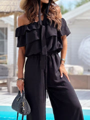 Black off-shoulder ruffle palazzo jumpsuit with tie-neck detail and wide legs.