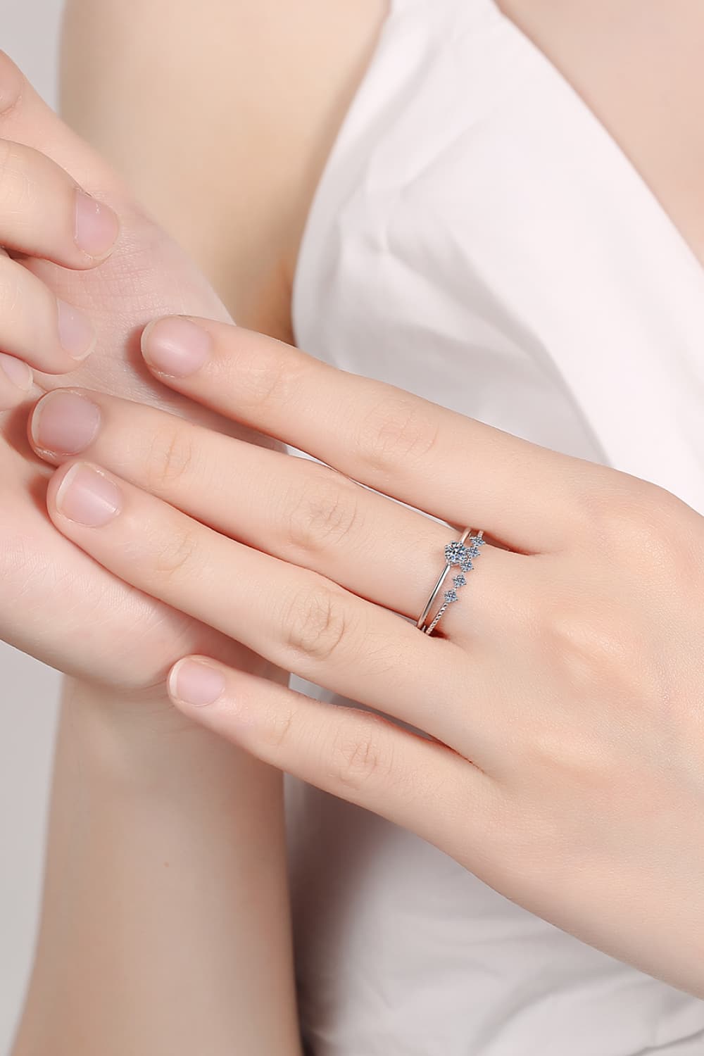 Silver layered rings with moissanite accents on a hand.