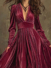 Cerise velvet maxi dress with deep V-neck, voluminous sleeves, and pleated skirt.