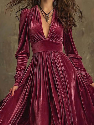 Cerise velvet maxi dress with deep V-neck, voluminous sleeves, and pleated skirt.