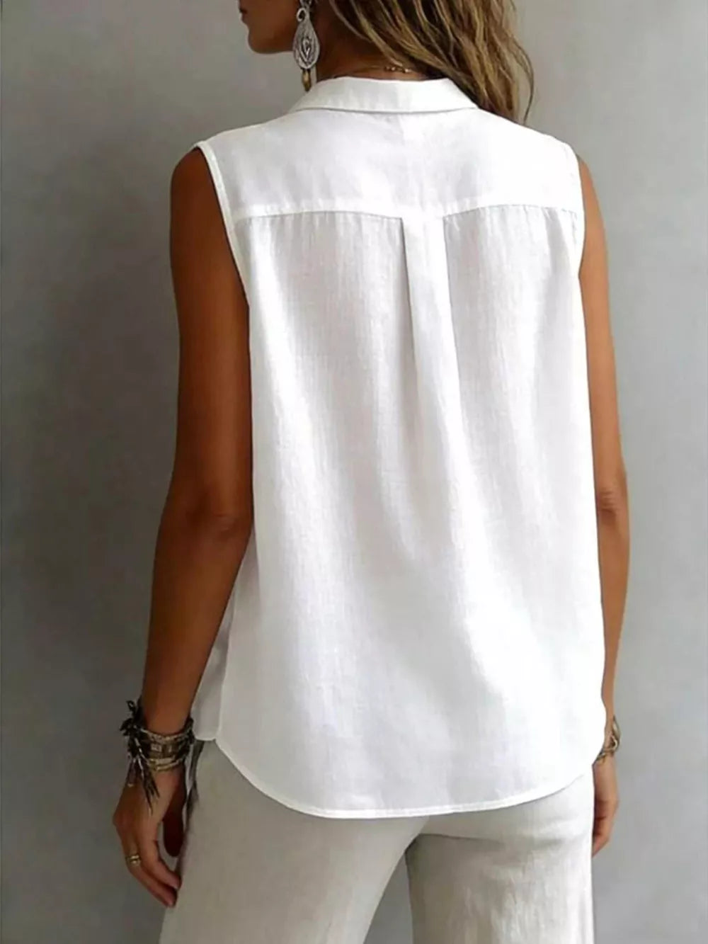 White sleeveless button-up shirt with collar and back pleats.