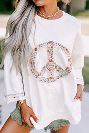 White sweatshirt with floral peace sign embellishment and trim on sleeves.