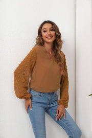 Camel V-neck blouse with textured pom-pom balloon sleeves.