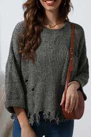 Distressed dark gray knit sweater with a pocket and frayed hem.