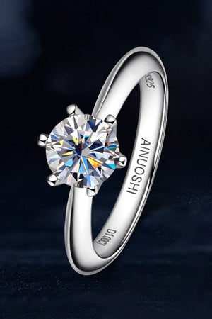 Silver solitaire moissanite engagement ring with six-prong setting and engraved band.