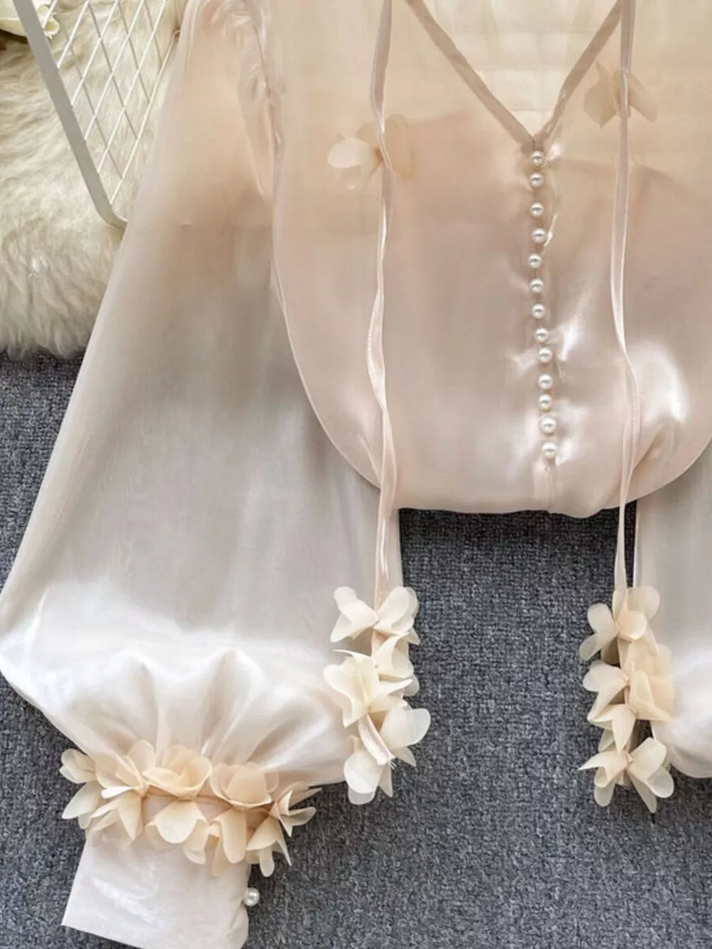 Apricot sheer organza shirt with pearl buttons and delicate floral appliqué on sleeves and hem.