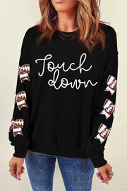 Black sweatshirt with white "Touchdown" script and football bow sleeve embellishments.
