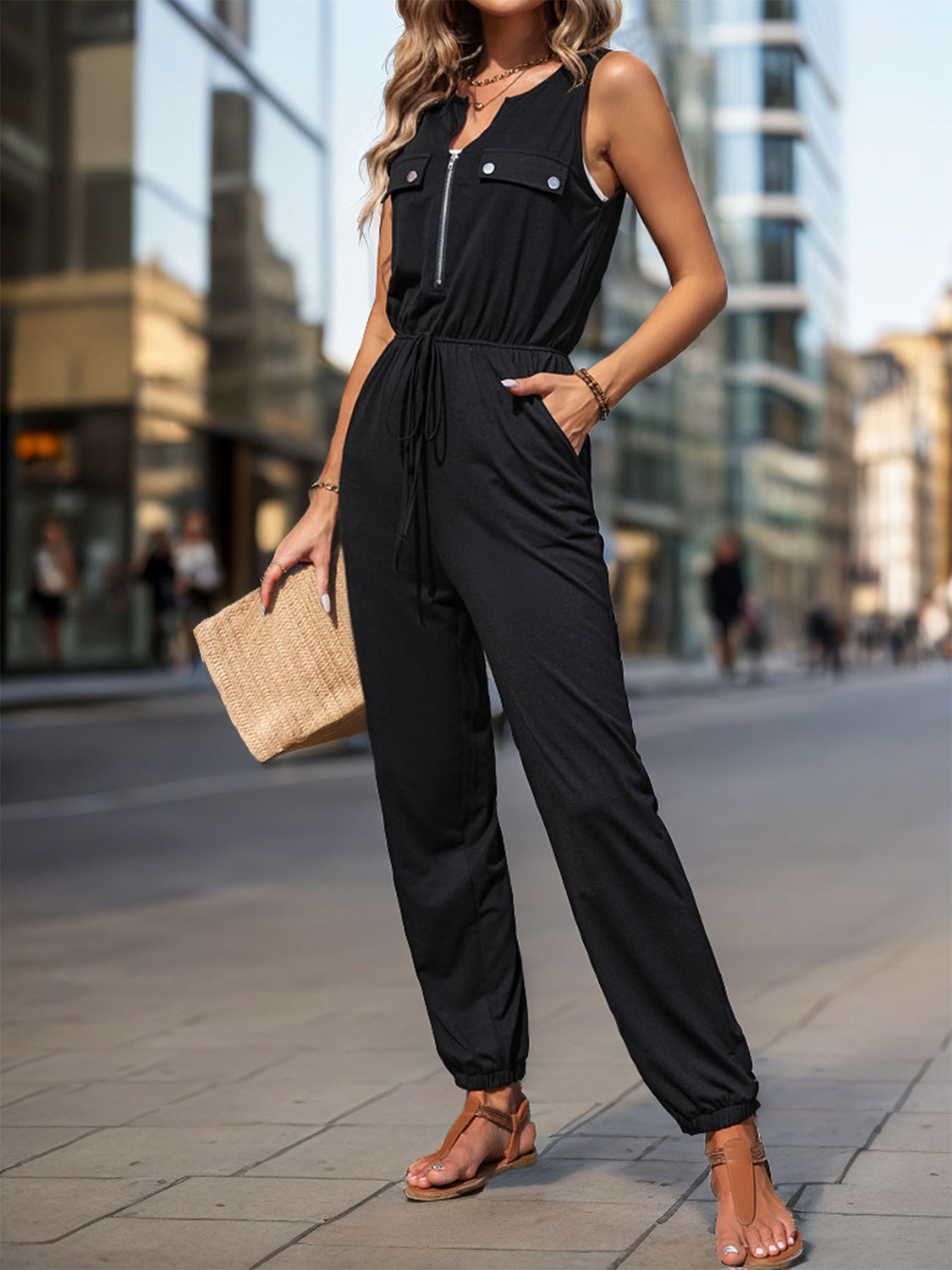 Black utility jumpsuit with zip-front, drawstring waist, and cuffed ankles.