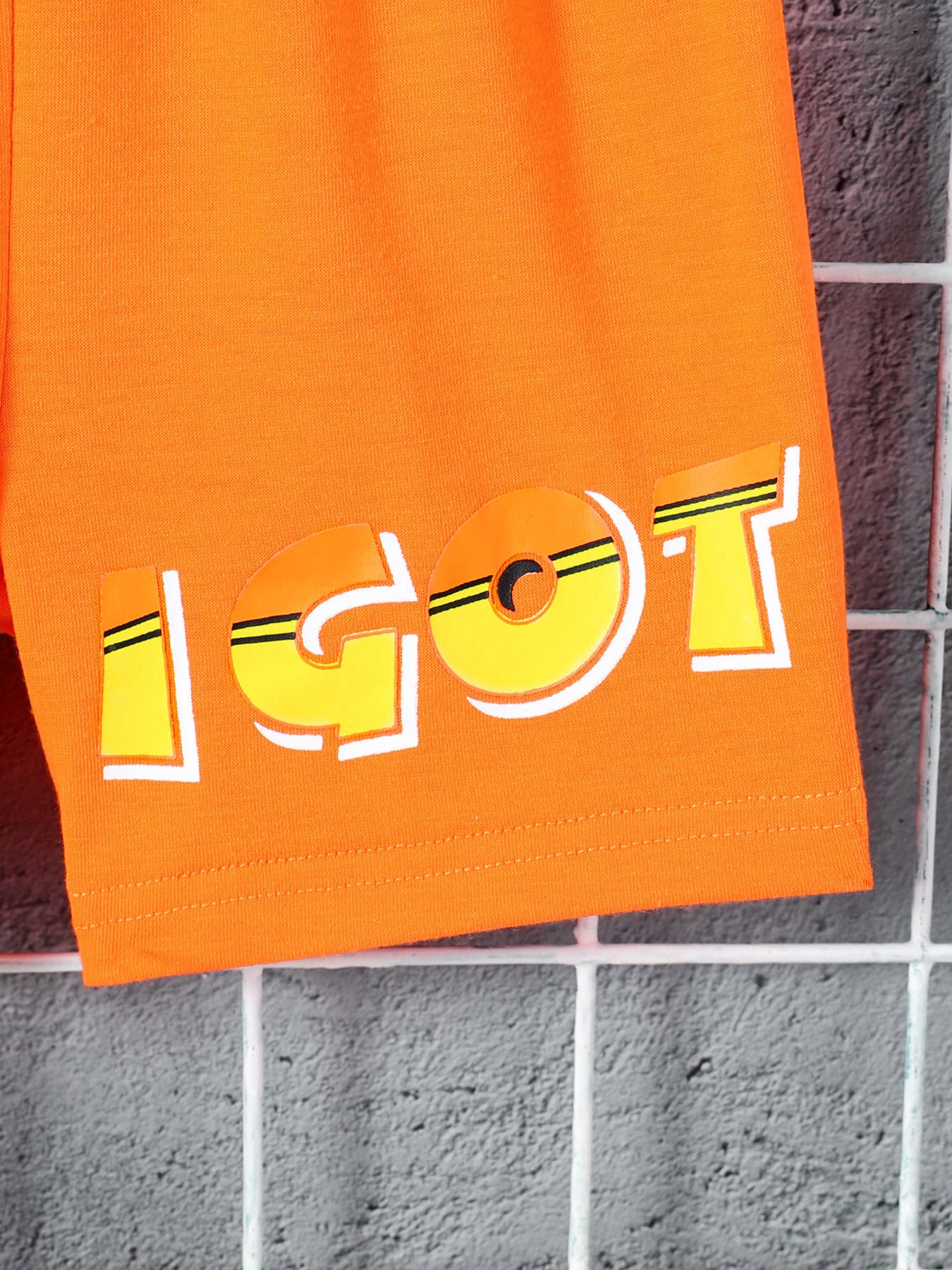 Orange boys' shorts with a bold yellow and white "IGOT" graphic print.