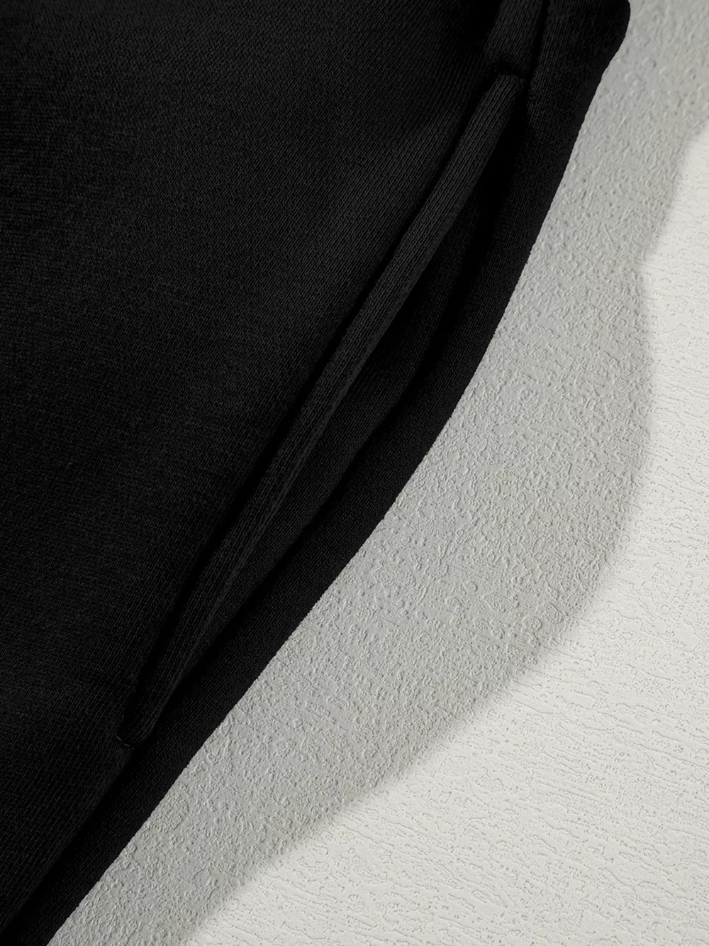 Black cotton joggers with drawstring detail and textured side panel