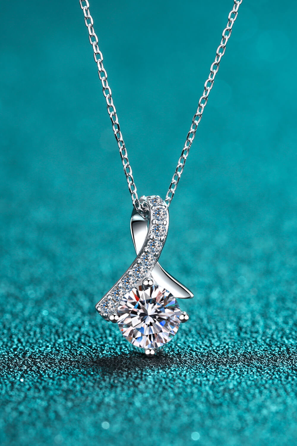 Silver solitaire pendant necklace with diamond-accented ribbon detail.