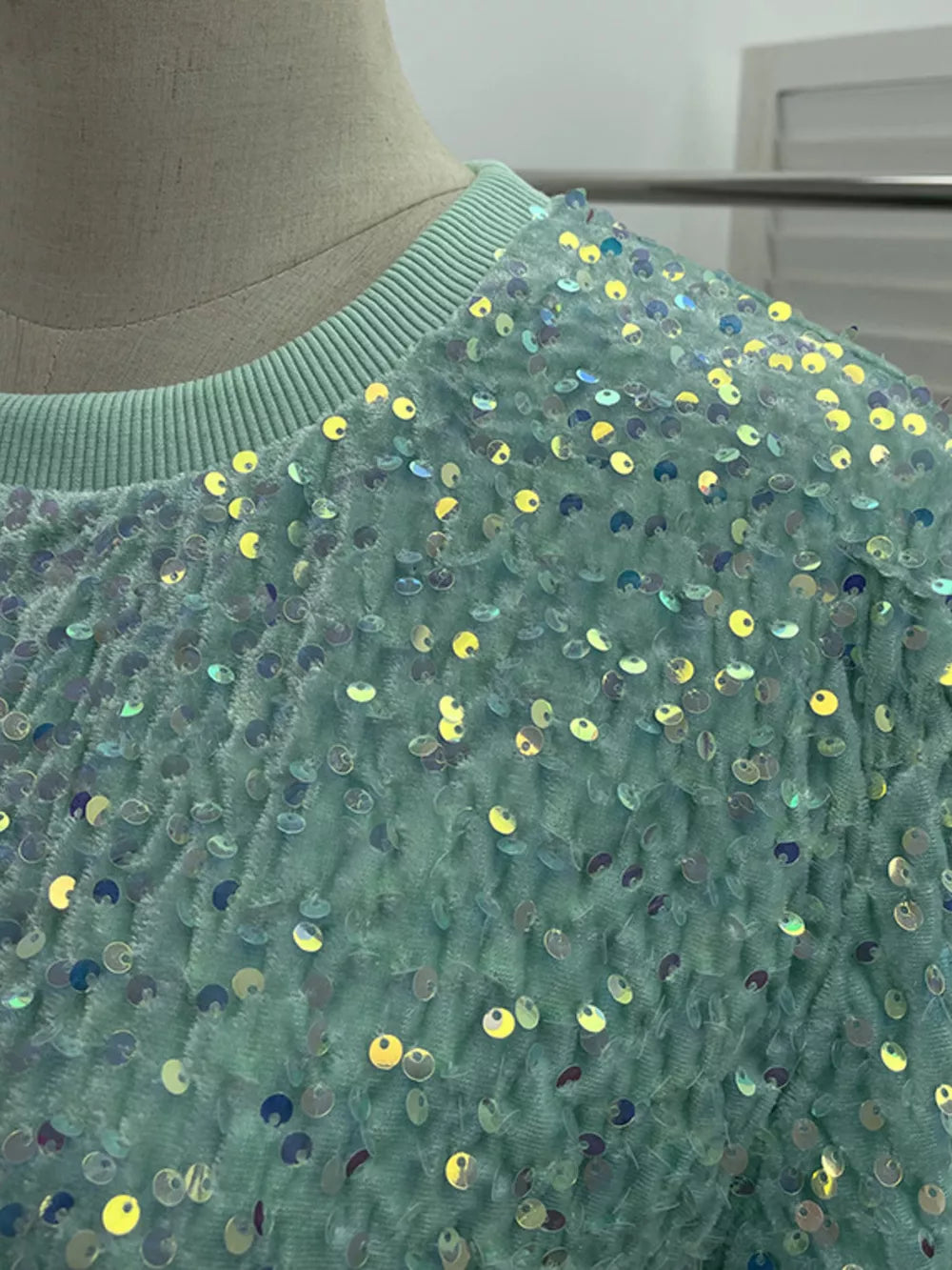 Green crew neck t-shirt with iridescent sequin embellishments and textured fabric.
