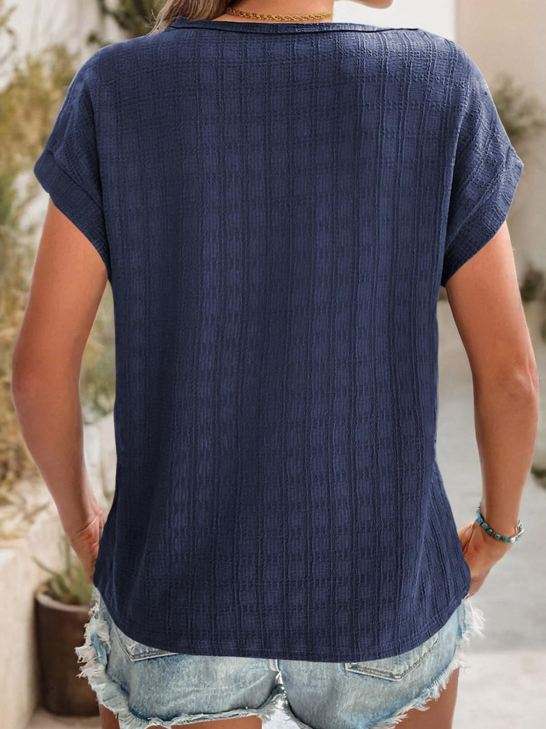 Navy woven texture cap-sleeve top with a relaxed fit, styled with denim shorts.
