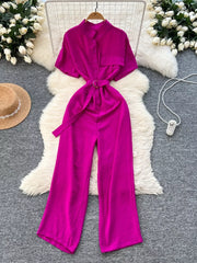 Rose red belted wide leg romper with short sleeves and a button-down front.