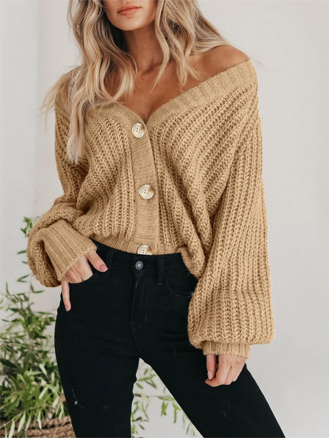 Camel knit cardigan with voluminous sleeves and button front, styled off-shoulder.