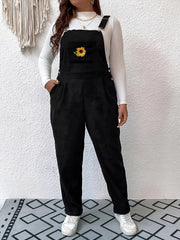 Black corduroy overalls with embroidered sunflower detail and relaxed fit.