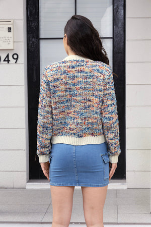 Textured bouclé knit cardigan with cream trim and multicolor flecks.