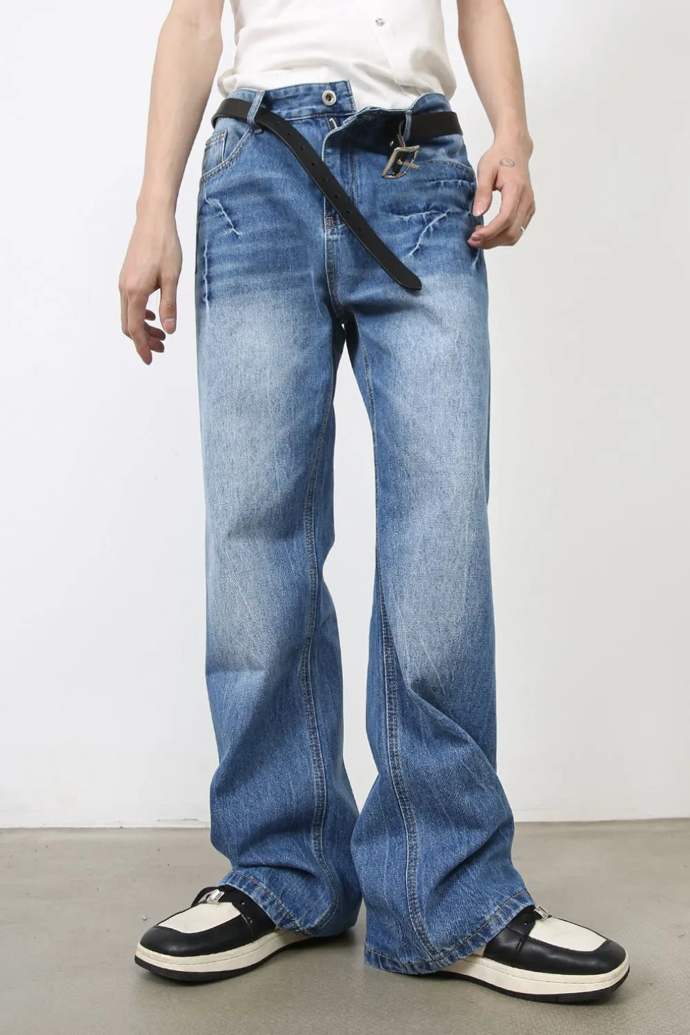 Baggy denim jeans in distressed wash medium blue with a black belt.