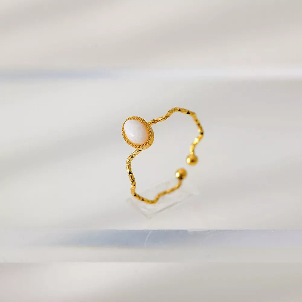 Wavy gold-plated ring with oval cream natural stone and textured band