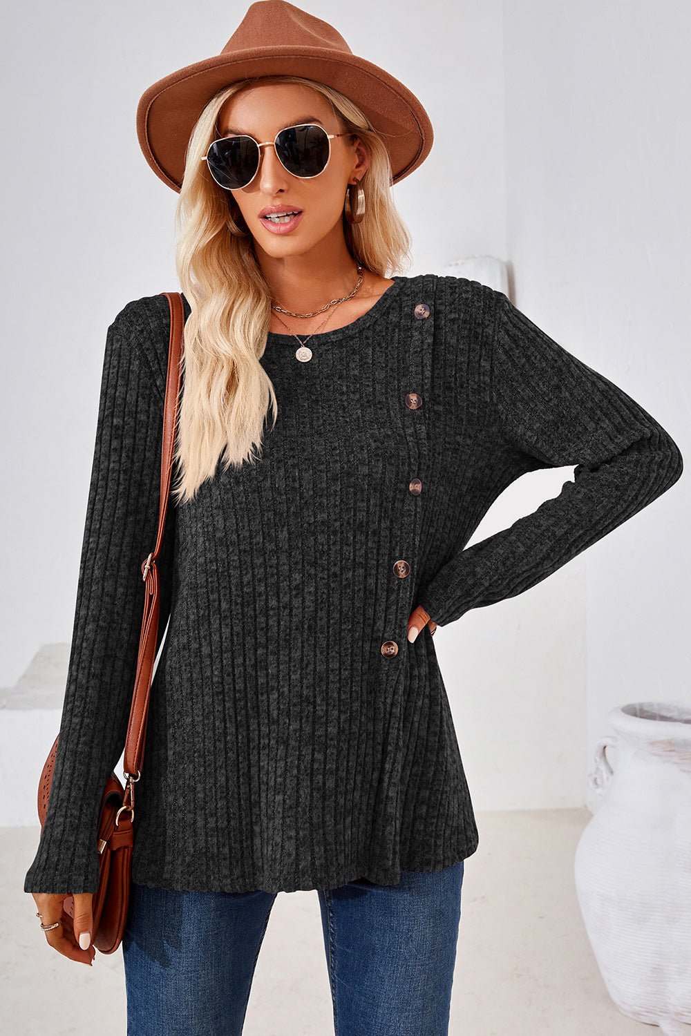 Black ribbed knit sweater with asymmetric button detail and long sleeves.