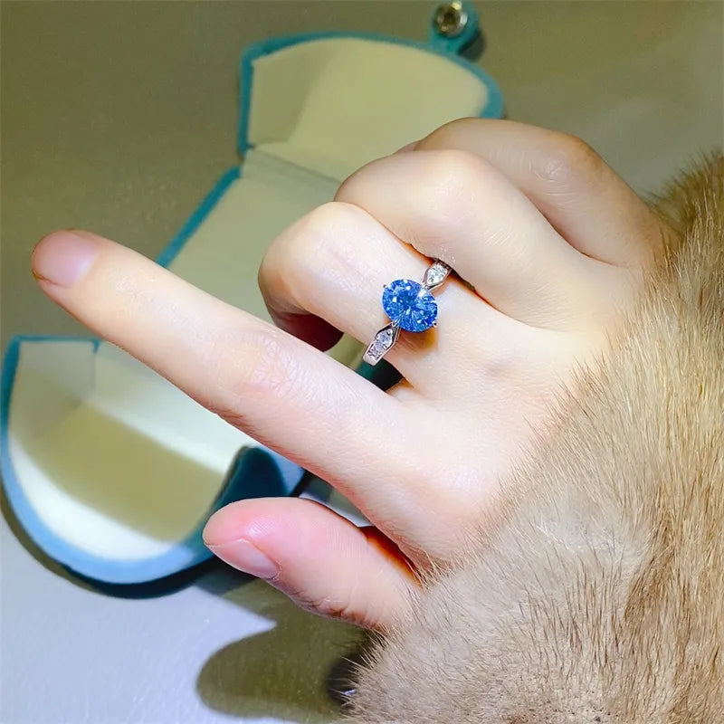 Sterling silver ring with oval blue moissanite and diamond halo accents.