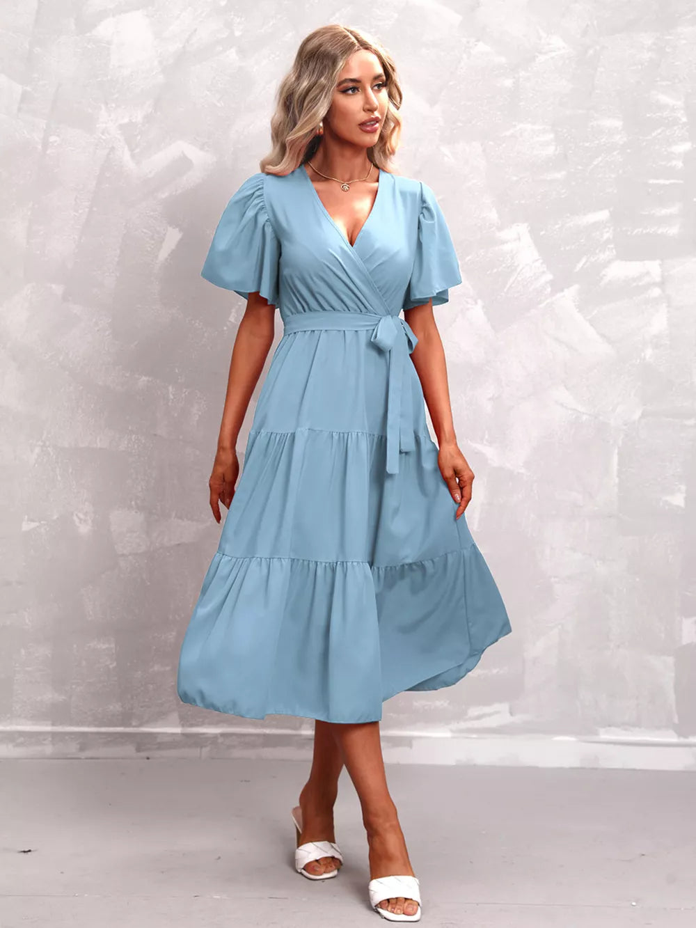 Light blue tiered midi dress with flutter sleeves, V-neck, and belted waist