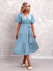 Light blue tiered midi dress with flutter sleeves, V-neck, and belted waist