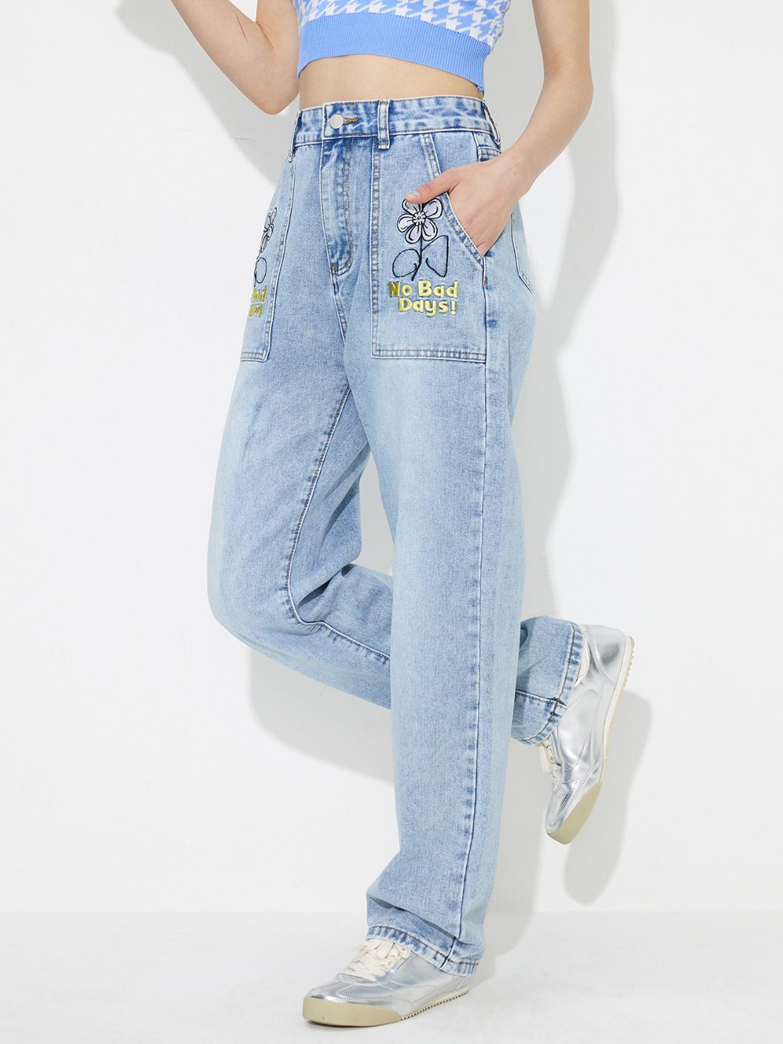 Light wash denim jeans with embroidered flower and "No Bad Days!" text on pocket.