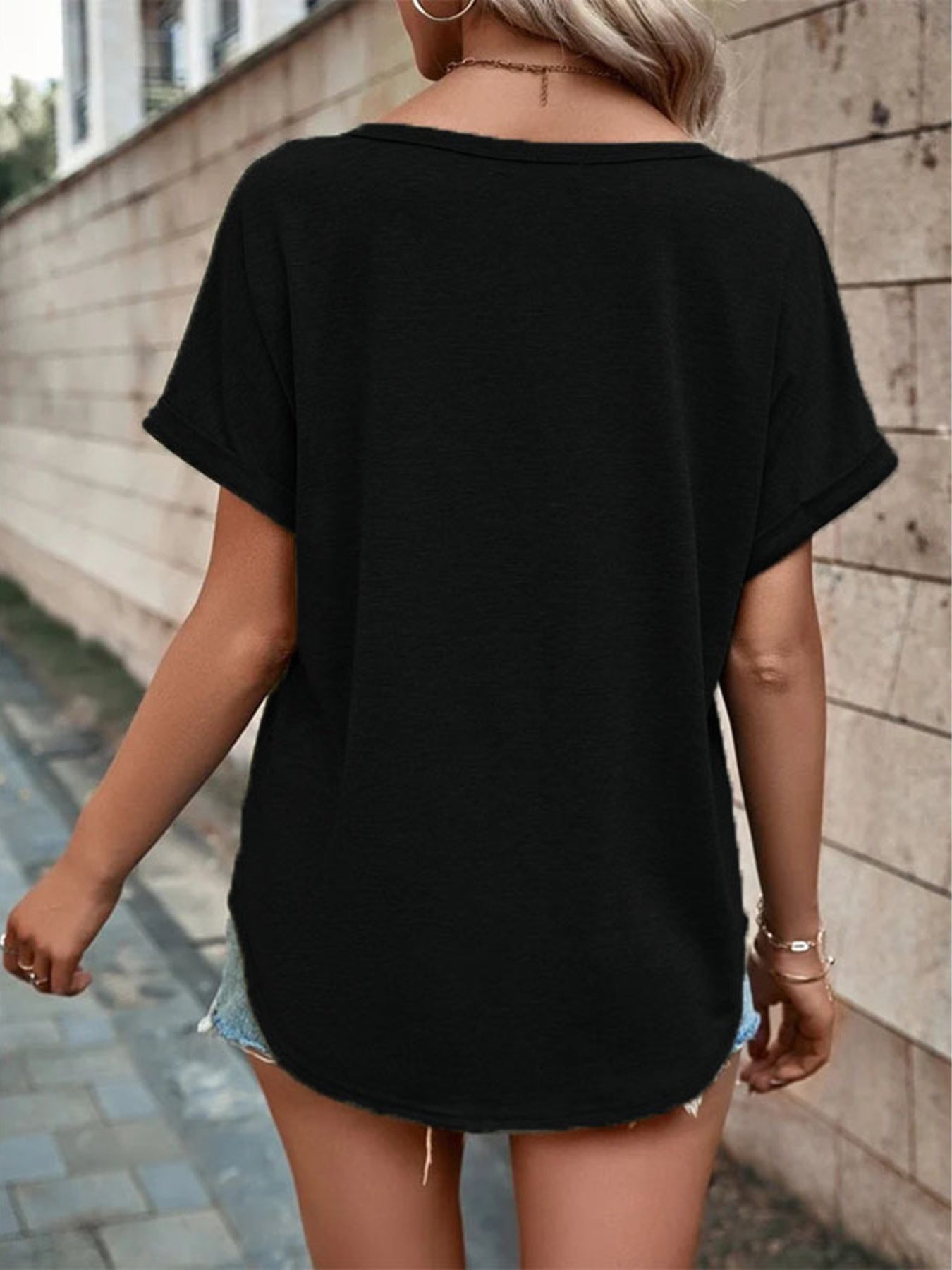 Black short sleeve t-shirt with decorative buttons and a V-neck, styled with denim shorts.