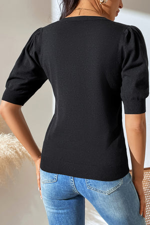 Black knit sweater with puff sleeves and ribbed cuffs.