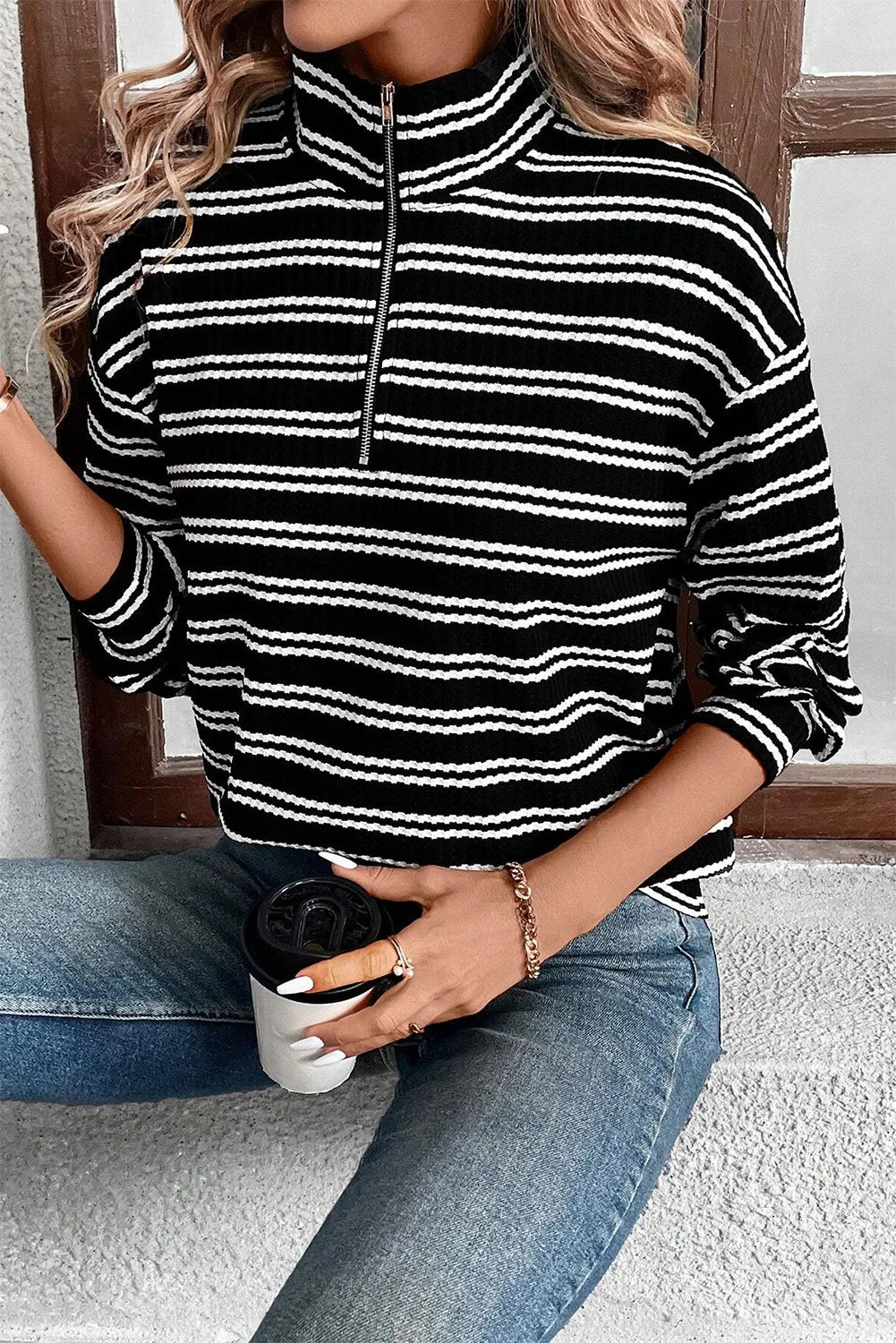 Black and white striped ribbed half-zip pullover sweater with a mock neck.