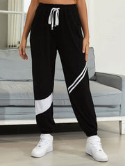 Black joggers with white diagonal panel details and drawstring waist.