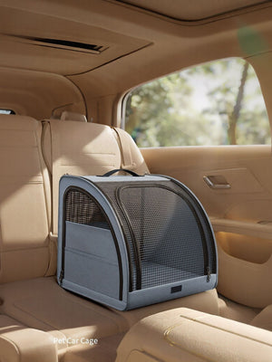 Gray pet carrier with mesh windows and zippered pockets, secured on car seat.