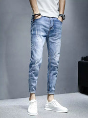 Men's light wash distressed slim fit jeans with rolled cuffs.