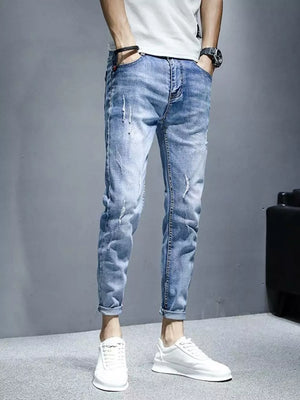 Men's light wash distressed slim fit jeans with rolled cuffs.