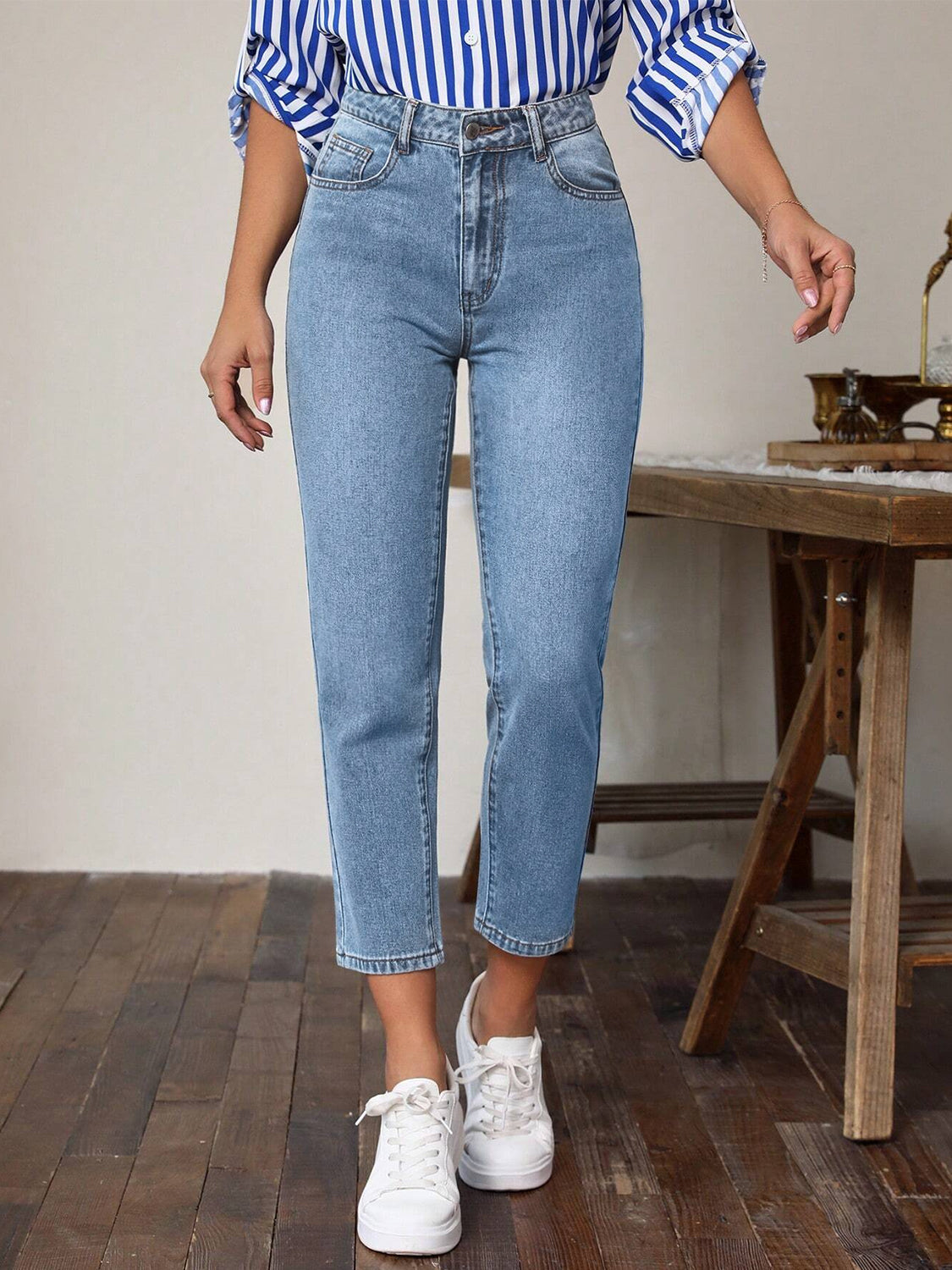 Light wash denim jeans with a slim-fit ankle cut, styled with white sneakers.