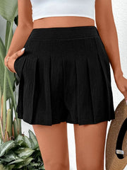 Black pleated shorts with pockets and a textured fabric.