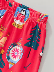 Children's red Christmas pajama set with festive holiday print including penguins in snow globes and ornaments.