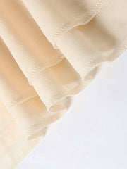 Backless ruffled mini dress detail showing layered fabric and ruffled hem in cream.