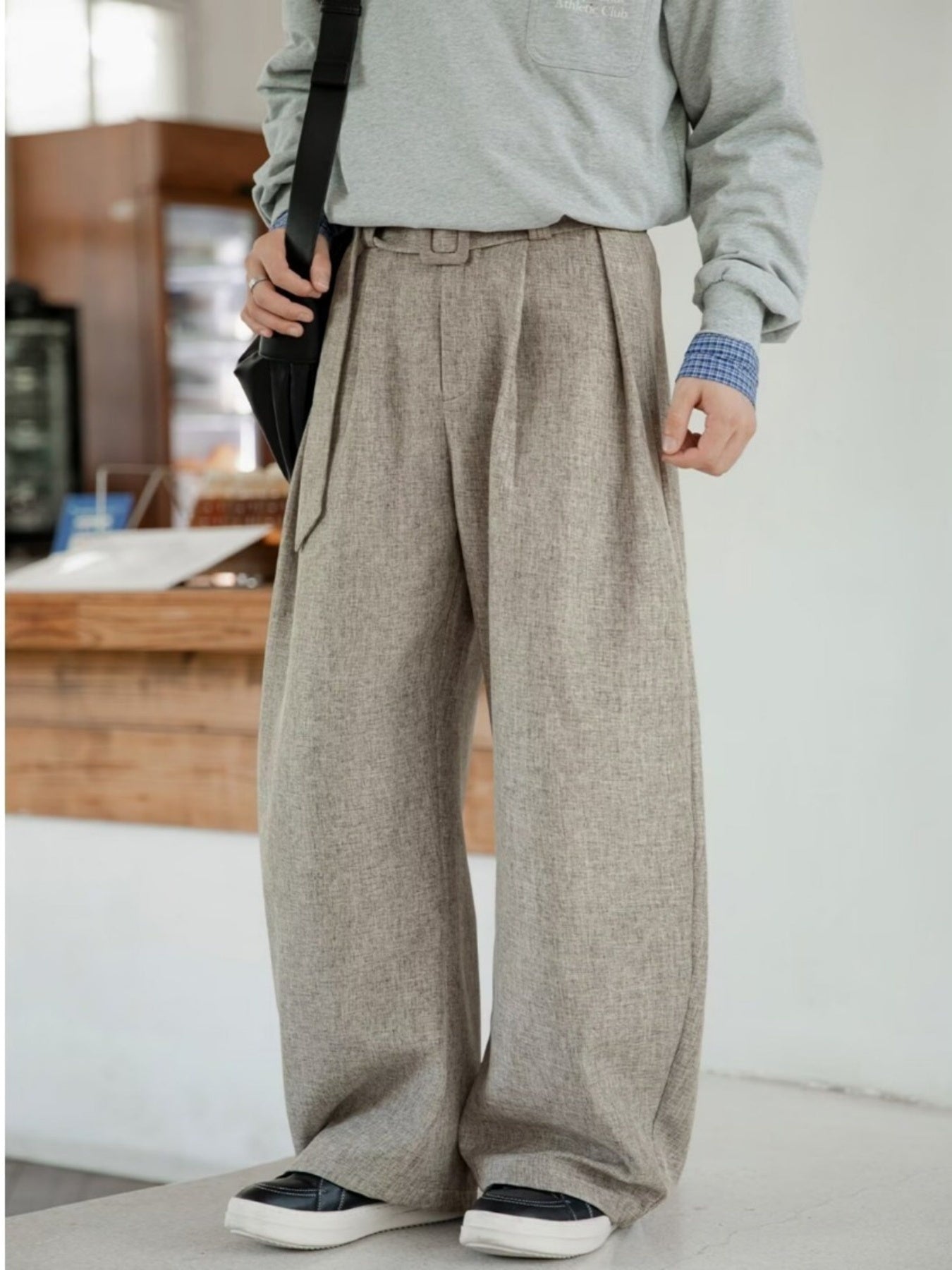 Men's wide leg trousers in beige with pleats and belt detail.