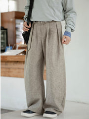 Men's wide leg trousers in beige with pleats and belt detail.
