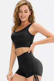 Seamless black scoop neck crop top with a wide band, shown on a model.