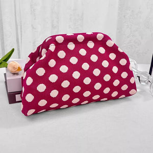 Vibrant knit clutch bag with white polka dots on a pink background.