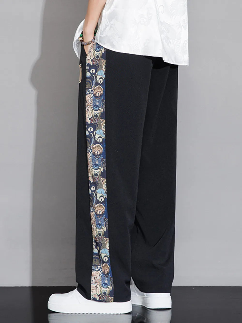 Men's black sweatpants with a printed side stripe detail.