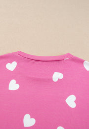 Hot pink long sleeve top with white hearts, round neck.