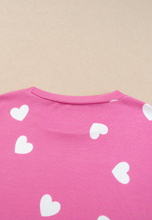 Hot pink long sleeve top with white hearts, round neck.