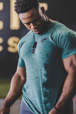 Performance raglan tee in heathered Army Green with a chest emblem and dog tag necklace.