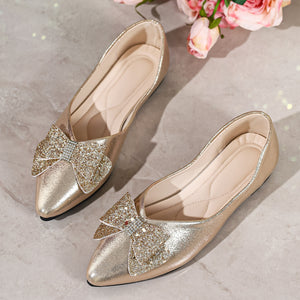 Gold pointed toe flats with glitter bows and rhinestone accents.